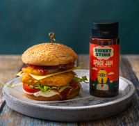 Hamburger on a plate with a bottle of Sweet Sting Space Jam mustard.